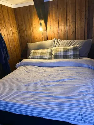 a bed with blue and white striped sheets and pillows at Charming Cabin With Fantastic View In Sjusjøen in Sjusjøen