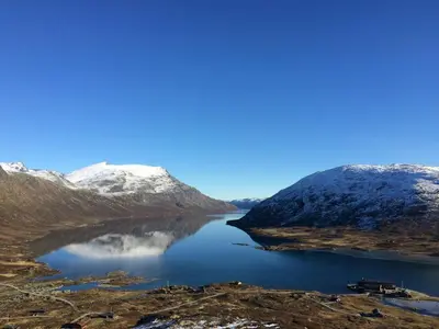 a lake in the middle of a snow covered mountain at Spectacular Cabin With View In Jotunheimen in Eidsbugarden