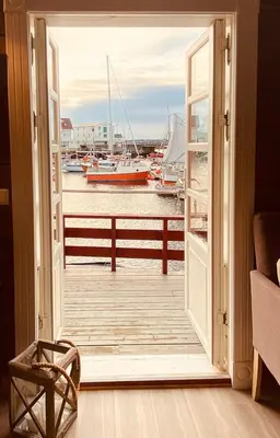 an open door to a dock with boats in the water at Charming Cabin On Veiholmen's Inner Harbor in Smøla