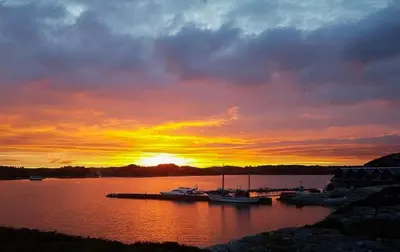 a sunset over a harbor with boats in the water at Seaside Dream Cabin With Jacuzzi in Steinsland