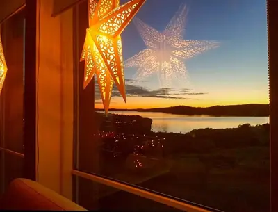 a window with christmas lights in a room at Seaside Dream Cabin With Jacuzzi in Steinsland