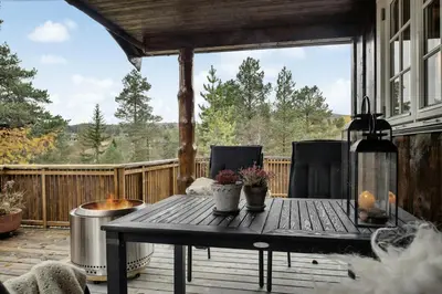 a patio with a table and chairs on a deck at Old Swiss Hotel Charm In Seljestad in Vinjeøra