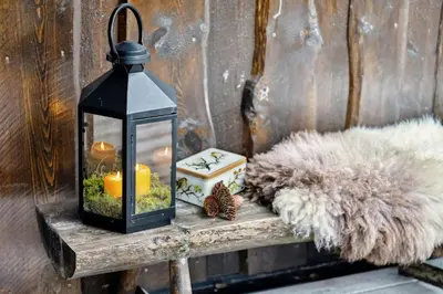 a lantern with a candle on a wooden table at Old Swiss Hotel Charm In Seljestad in Vinjeøra