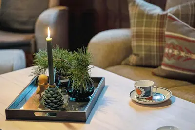a candle on a table with plants and a cup of coffee at Old Swiss Hotel Charm In Seljestad in Vinjeøra