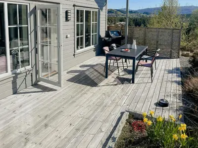 a wooden deck with a table and chairs on a house at Cozy Family Cabin Surrounded By Idyllic Islands in Fitjar