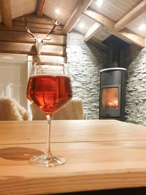 a glass of wine sitting on a table with a fireplace at Mountain Cabin With A View Over Jotunheimen in Tretten