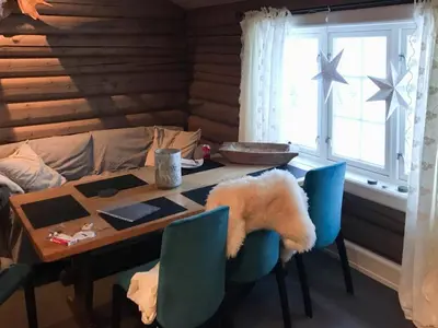 a dining room table with blue chairs and a couch at Mountain Cabin With A View Over Jotunheimen in Tretten