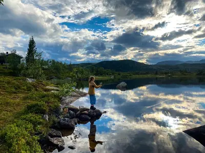 a young boy standing on rocks in front of a lake at Cabin With Award-Winning Design On Norefjell in Eggedal
