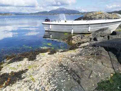a boat sitting on the shore of a body of water at Charming Cottage At The Edge Of The Sea in Lykling