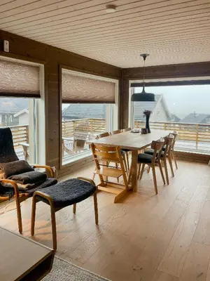 a dining room with a table and chairs and windows at Modern Family Cabin At Sjusjøen in Sjusjøen