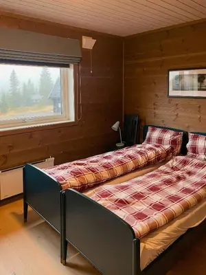 two beds in a room with a window at Modern Family Cabin At Sjusjøen in Sjusjøen