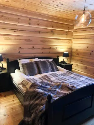 a bedroom with wooden walls and a bed with two lamps at Spacious Log Cabin Near Hardangervidda in Uvdal