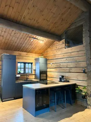 a kitchen with wooden walls and a large island in a room at Spacious Log Cabin Near Hardangervidda in Uvdal