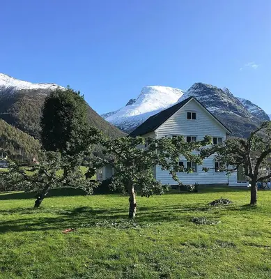 a house with snow covered mountains in the background at Charming House In Loen, In The Heart Of Nordfjord in Loen
