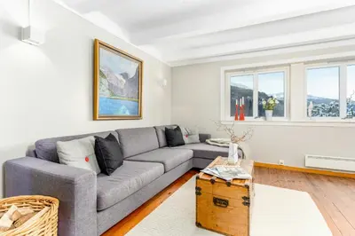 a living room with a gray couch and two windows at Charming House In Loen, In The Heart Of Nordfjord in Loen