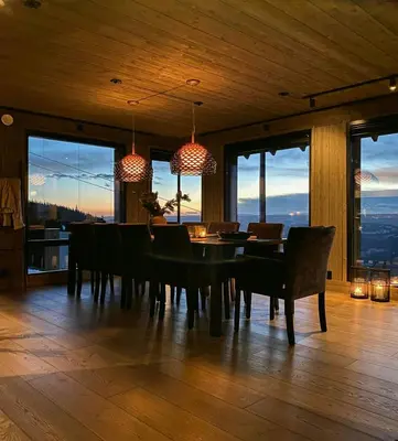 a dining room with a table and chairs and windows at Ski Inski Out-Hytte I Hafjell Med Udsigt in Øyer