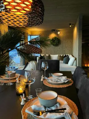 a dining room with a table with plates and wine glasses at Ski Inski Out-Hytte I Hafjell Med Udsigt in Øyer