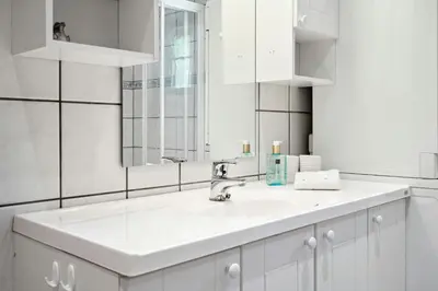 a white bathroom with a sink and a mirror at Mountain Cabin With Great Views in Austbygdi
