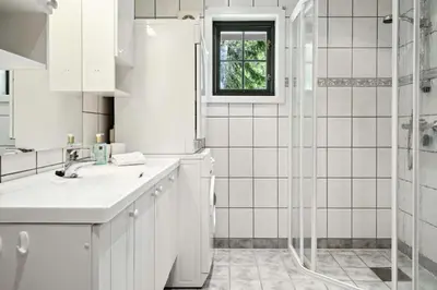 a white bathroom with a sink and a shower at Mountain Cabin With Great Views in Austbygdi