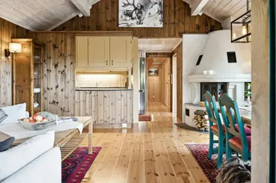 a kitchen and living room with a table and chairs at Mountain Cabin With Great Views in Austbygdi