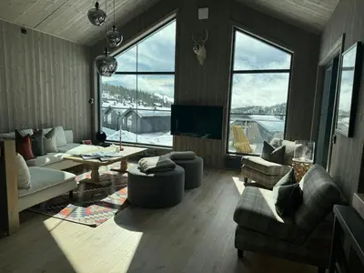 a living room with couches and a tv and windows at Modern Family Cabin In Norefjell Ski-Inout in Surteberg