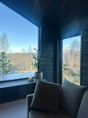 a living room with a couch and a large window at Idyllic Cabin With Panoramic Mountain Views in Nerskogen