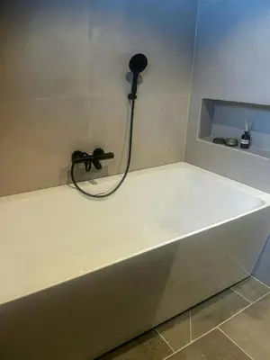 a white bath tub with a black shower nozzle at Idyllic Cabin With Panoramic Mountain Views in Nerskogen