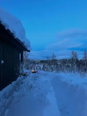 a snow covered road next to a building with a light on it at Idyllic Cabin With Panoramic Mountain Views in Nerskogen
