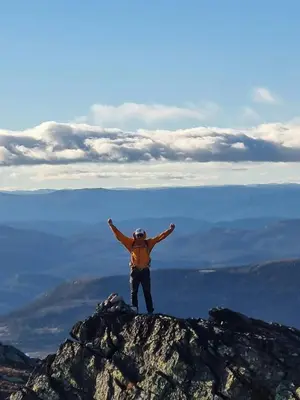 a man standing on top of a mountain with his arms up at Mountain Cabin With Stunning Views, Sauna & Lake in Eggedal