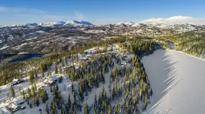 an aerial view of a lake with trees and snow covered mountains at Mountain Cabin With Stunning Views, Sauna & Lake in Eggedal