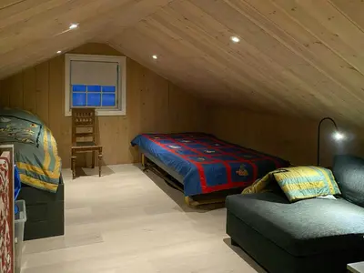 a room with a bed and a couch in a attic at Mountain Cabin With Sauna, Jacuzzi And Views in Nord Torpa