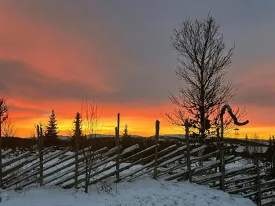 a fence in the snow with a sunset in the background at Family Cabin With Views In Sør-Fron in Sør-Fron