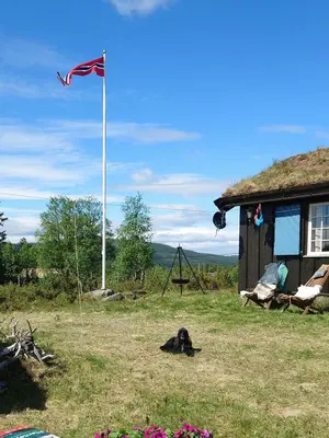 a flag on a pole next to a house at Mountain Cabin With Wood-Fired Sauna And A View in Golsfjellet