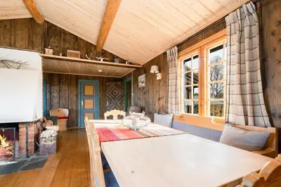 a living room with a table and a fireplace at Mountain Cabin With Wood-Fired Sauna And A View in Golsfjellet
