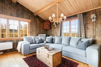 a living room with a blue couch and a table at Mountain Cabin With Wood-Fired Sauna And A View in Golsfjellet