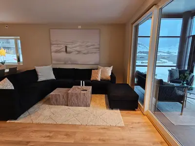 a living room with a black couch and a table at Stor og ny leilighet med fjordutsikt in Sande