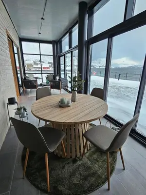 a wooden table and chairs in a room with windows at Stor og ny leilighet med fjordutsikt in Sande