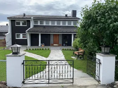 a house with a gate in front of a yard at Central and modern apartment in Hamar
