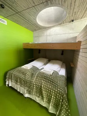 a bedroom with a bed with a green wall at Støkkøya Strandhotell in Hosen