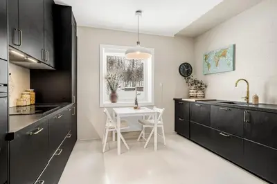 a kitchen with black cabinets and a white table at Central 4-bedroom by Lerkendal in Trondheim