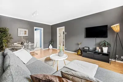 a living room with a couch and a tv on a wall at Central 4-bedroom by Lerkendal in Trondheim