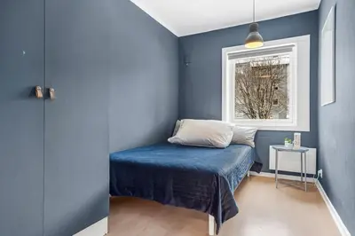 a blue bedroom with a bed and a window at Central 4-bedroom by Lerkendal in Trondheim