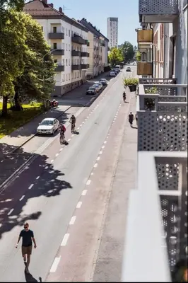 a man walking down a street with bicyclists on the road at Sentral leilighet Trondheim in Trondheim