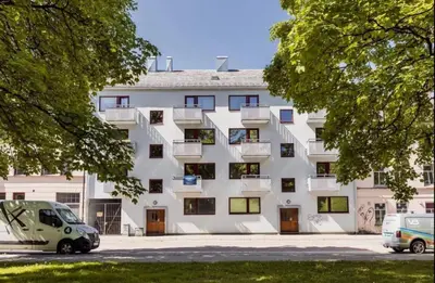 a white building with two cars parked in front of it at Sentral leilighet Trondheim in Trondheim