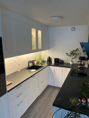 a kitchen with white cabinets and a black counter top at Ski VM in Trondheim