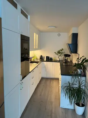 a kitchen with white cabinets and black counter tops at Trondheim in Trondheim