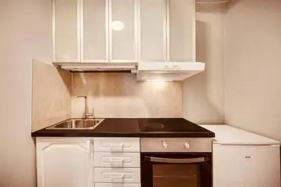 a small kitchen with white cabinets and a sink at Live the history in Bergens heart - Stay unique in Bergen