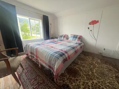 a bedroom with a bed with a red flower on the wall at Fiskesenter Birkeland Guesthouse in Vestnes