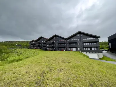 a building on top of a grassy field at Homey Apartment Steps From Dining And Activities! in Beitostøl