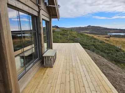 a wooden deck with a bench on the side of a building at Utsikten in Sør-Fron